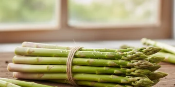 Freshly harvested green asparagus spears on a wooden table, ready for cooking