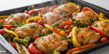 Delicious one-pan chicken and vegetable meal on a baking sheet, ready to eat.