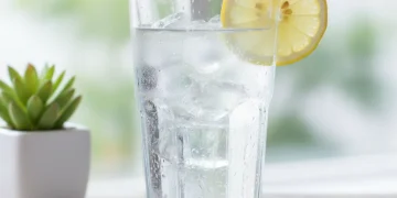 Refreshing glass of water with lemon slice on a wooden table
